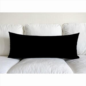 May include: A black rectangular lumbar pillow on a white couch.