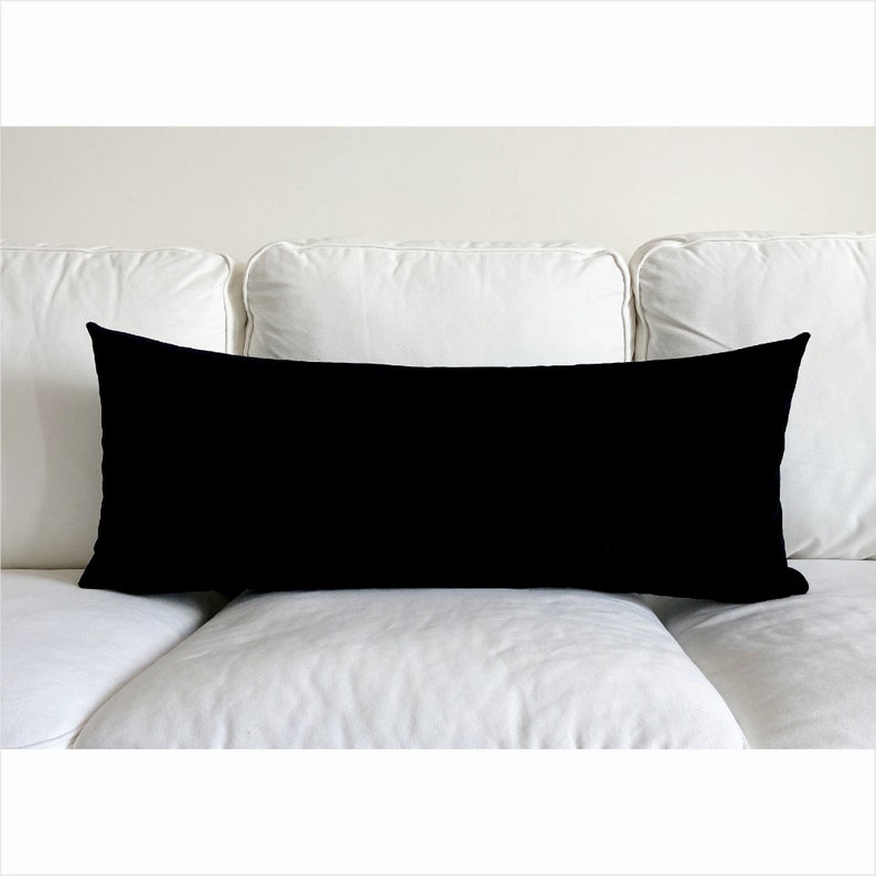 May include: A black rectangular lumbar pillow on a white couch.