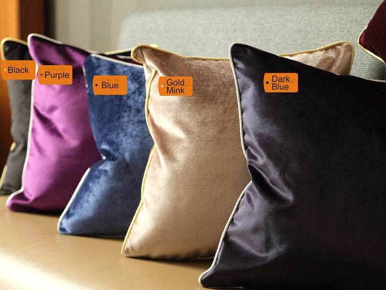 Puede incluir: Cinco cojines decorativos de diferentes colores y texturas. Los cojines est&aacute;n dispuestos en una fila en un sof&aacute;. Los cojines est&aacute;n etiquetados con los siguientes colores: Negro, Morado, Azul, Vis&oacute;n Dorado y Azul Oscuro.