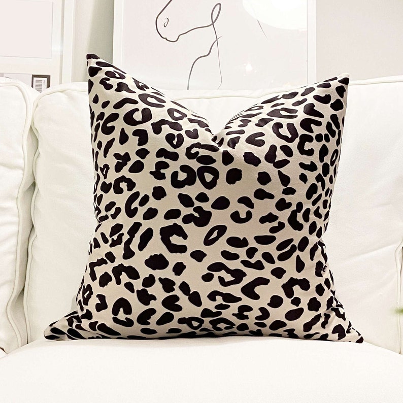 Puede incluir: Una almohada beige con estampado de leopardo negro.