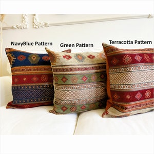 May include: Three decorative throw pillows with different patterns. The pillow on the left has a navy blue background with red, orange, and white geometric patterns. The middle pillow has a green background with beige, red, and orange geometric patterns. The pillow on the right has a terracotta background with red, orange, and beige geometric patterns.