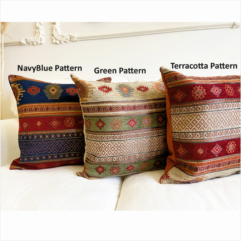 May include: Three decorative throw pillows with different patterns. The pillow on the left has a navy blue background with red, orange, and white geometric patterns. The middle pillow has a green background with beige, red, and orange geometric patterns. The pillow on the right has a terracotta background with red, orange, and beige geometric patterns.