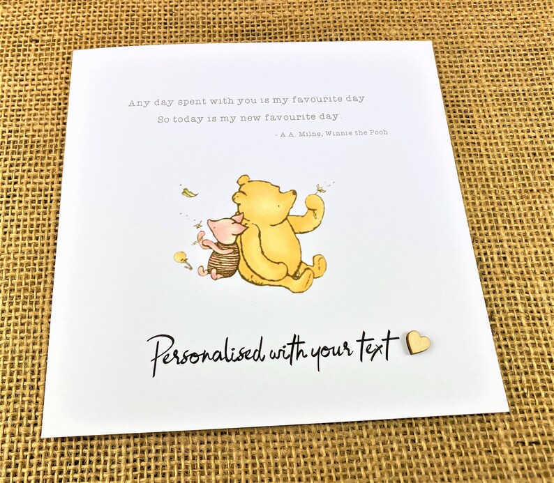May include: A greeting card featuring Winnie the Pooh and Piglet. The card has the text "Any day spent with you is my favourite day. So today is my new favourite day - A.A. Milne, Winnie the Pooh." The card also says "Personalised with your text."