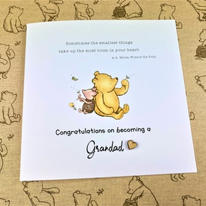 May include: A Winnie the Pooh and Piglet illustration on a white card with the text "Sometimes the smallest things take up the most room in your heart - A.A. Milne, Winnie the Pooh" and "Congratulations on becoming a Grandad".
