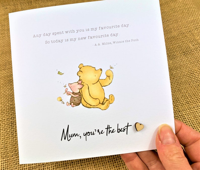 May include: A greeting card featuring Winnie the Pooh and Piglet. The card has the text "Any day spent with you is my favourite day. So today is my new favourite day - A.A. Milne, Winnie the Pooh." and "Mum, you're the best."