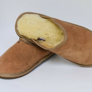 May include: A pair of brown suede slippers with a sheepskin lining. The slippers have a simple design and are ideal for keeping your feet warm in the winter.