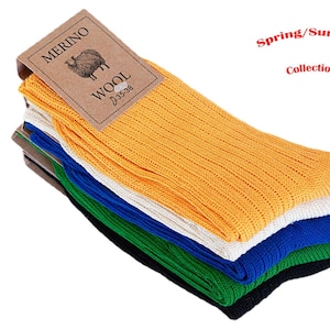 May include: A pile of ribbed Merino wool socks in various colours: yellow, white, blue, green, and black. Each pair has a tag that reads "Merino Wool". The text "Spring/Summer Collection!" is also visible.