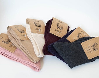 May include: A collection of folded wool socks in various colors, including pink, beige, white, burgundy, navy, and charcoal gray. Each pair has a tag with a goat illustration and the word "WOOL". The socks are sized 35-38.
