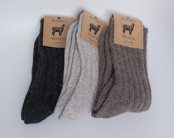 May include: Three pairs of alpaca wool socks in gray, white, and brown. Each pair has a tag with an alpaca illustration and the text "ALPAKA WOOL 39-42".