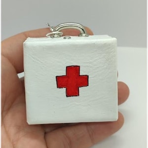 Miniature first-aid suitcase for dolls and dollhouse with 12 items: tiny notebook, scissors, patch, pills, glass jar, watter.