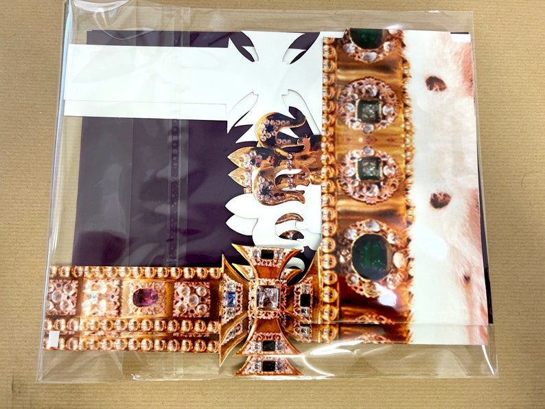 May include: A gold crown with green and red jewels, a white fur lining, and a gold cross with a purple background.