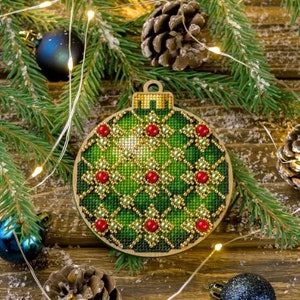 Könnte beinhalten: Ein grüner Weihnachtsbaumschmuck mit goldenen und roten Perlen. Der Schmuck ist aus Holz und hat einen Perlenrand.
