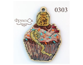 May include: A wooden cupcake ornament with a brown, pink, and yellow frosting design. The cupcake has a yellow swirl on top and is decorated with red hearts, orange and blue sprinkles. The ornament has a hole at the top for hanging and the number 0303 is printed on the right side.