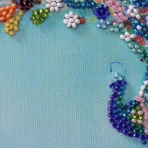 May include: A blue background with a border of colorful beads arranged in a floral pattern. The beads are in shades of blue, green, white, pink, and orange.