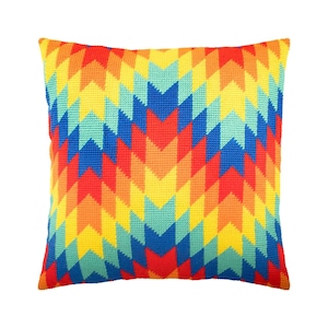 May include: A square throw pillow featuring a vibrant needlepoint texture with a repeating chevron pattern. The design consists of vertical columns of alternating colors including bright yellow, orange, red, light blue, and deep royal blue.