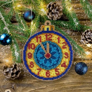 May include: A round, wooden Christmas ornament shaped like a clock face with blue, yellow, and red accents. The clock face shows the time as 11:59.