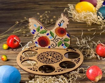 Può includere: Un porta uova in legno a forma di gallina con un design a perline. La gallina è decorata con fiori e foglie colorati. Il porta uova ha sei slot per le uova.