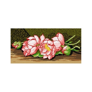 Puede incluir: Un primer plano de un bordado de punto de cruz que representa flores de loto rosas y blancas con hojas y capullos verdes sobre una superficie de madera marrón.