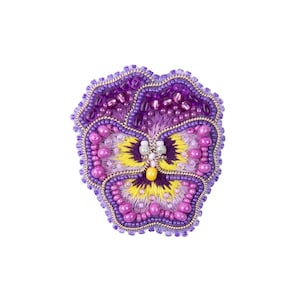 May include: A purple, pink and yellow beaded flower brooch. The flower is embroidered with beads and has a yellow centre.