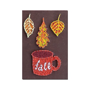 Puede incluir: Arte de hilo de una taza roja con la palabra "otoño" dentro. La taza está rodeada de tres hojas de colores.