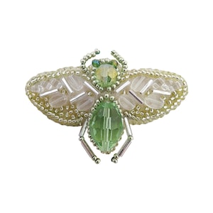 May include: A green and white beaded bee brooch with a large green crystal in the center. The bee is surrounded by small white beads and silver beads.