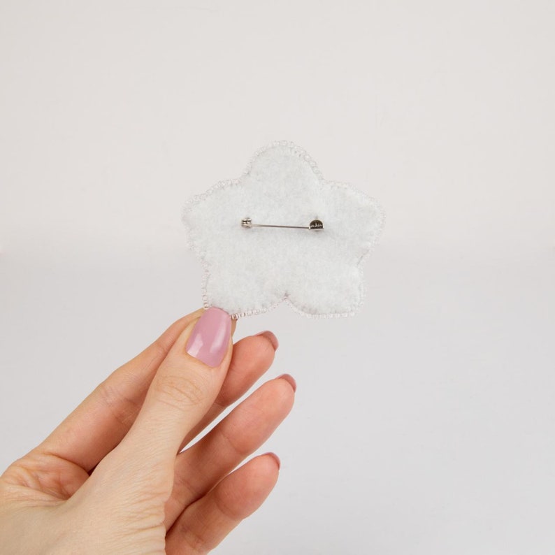 Pu&ograve; includere: Broche a forma di stella in feltro bianco con una spilla argentata sul retro.