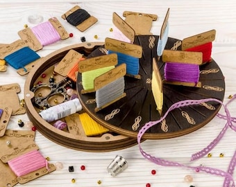 May include: A wooden thread organizer with a dark brown finish, holding spools of colorful thread. The organizer is round with slots for the spools, and a tray holds scissors, beads, and other sewing notions. Various colors of thread are visible.