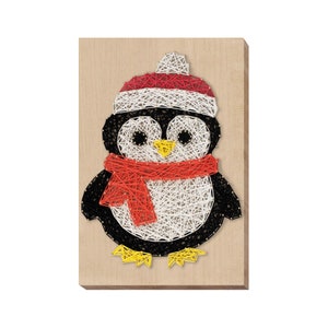 May include: A string art penguin wearing a red and white hat and a red scarf. The penguin is made of white, black, red, and yellow string wrapped around nails hammered into a wooden board.