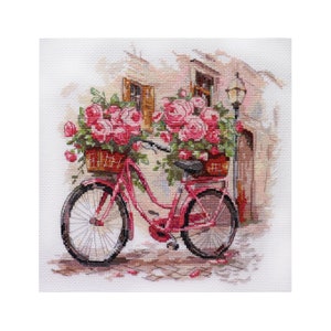 May include: A pink bicycle with a basket full of pink roses. The bicycle is parked in front of a building with a window and a lamppost.