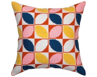 Puede incluir: Un cojín cuadrado de punto de aguja con un patrón geométrico repetitivo de formas de hojas curvas. El diseño se compone de una cuadrícula de cuadrados en colores azul marino, amarillo brillante, rosa suave y blanco, con acentos naranjas.