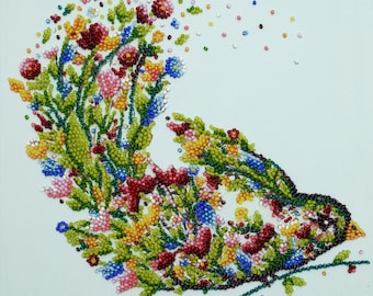 May include: A square wall art piece featuring a bird silhouette composed of colorful beads and rhinestones. The bird is filled with floral patterns in red, yellow, blue, and green, with scattered beads trailing off the tail against a pale blue background.