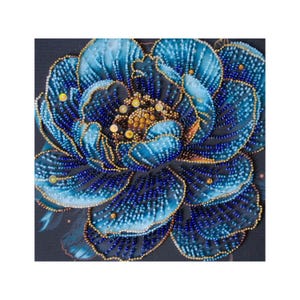 Könnte beinhalten: Nahaufnahme eines detaillierten Blumendesigns. Das Bild zeigt eine große, stilisierte Blume mit geschichteten Blütenblättern in Blautönen, verziert mit goldenen und gelben Perlen. Der Hintergrund ist eine dunkle, gedämpfte Farbe.