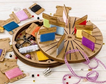 May include: A wooden thread organizer with a rotating wheel that holds spools of thread. The organizer has a lid that opens to reveal a compartment for storing other sewing supplies. The organizer is surrounded by colorful spools of thread, beads, and a thimble.