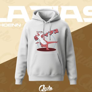 Puede incluir: Sudadera con capucha blanca con bolsillo delantero y un gr&aacute;fico de un personaje de dibujos animados rojo y blanco con texto japon&eacute;s. La palabra "LATIAS" est&aacute; impresa en letras blancas grandes encima de la sudadera, con "HOENN" debajo.