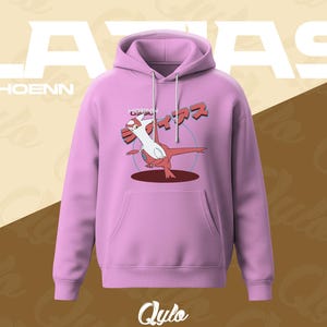 Puede incluir: Una sudadera con capucha de color lila claro con bolsillo de canguro y capucha. La parte delantera presenta un personaje de dibujos animados rojo y blanco con texto japon&eacute;s encima. La palabra "LATIAS" est&aacute; impresa en blanco en la parte superior, con "HOENN" debajo.
