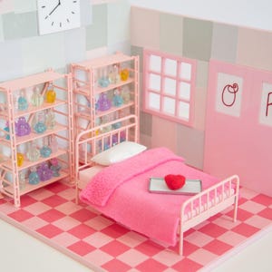 May include: A miniature pink bedroom scene with a bed, shelves, and a clock. The bed has a pink blanket and a red heart on a tray. Shelves display colorful bottles. The floor is a pink and red checkerboard pattern.