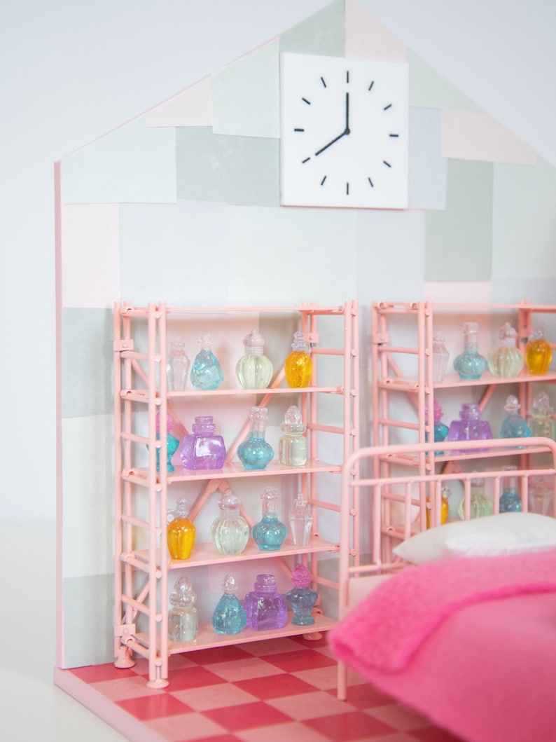May include: A miniature dollhouse bedroom with pink shelving units filled with colorful glass bottles. A white clock hangs on the wall above the shelves. The room has a pink and white checkered floor and a pink bed with a pink blanket.