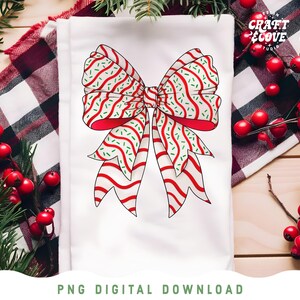 May include: A white towel featuring a large, festive bow design. The bow has red outlines and is decorated with red and green stripes and sprinkles. The towel is surrounded by red berries and greenery, with the text "PNG DIGITAL DOWNLOAD" at the bottom.
