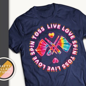 May include: Navy blue t-shirt with a colorful tie-dye design featuring flags and the words "Spin Toss Live Love Spin" in a circular pattern. The design includes hearts and the text "Crafty Collage Studio".