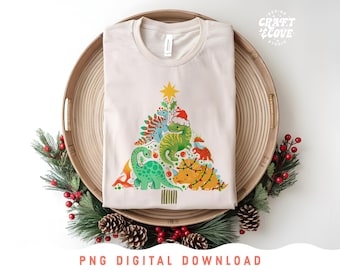May include: A beige t-shirt with a Christmas tree design featuring dinosaurs wearing Santa hats. The tree is decorated with ornaments and a star on top. The text "CRAFT & COVE" is visible in the top right corner of the image.