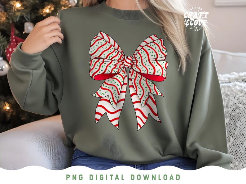 May include: An olive green sweatshirt featuring a large, festive bow graphic. The bow has red and white striped ribbons with green sprinkles. The design is a PNG digital download. The text "Design Craft & Cove Studio" is visible.