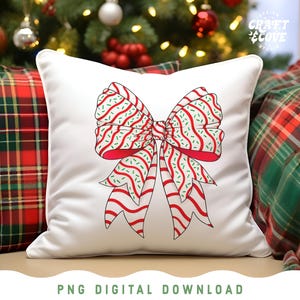 May include: White square pillow with a large red and white bow design. The bow has red stripes and green sprinkles. The pillow is on a couch with plaid pillows and a Christmas tree in the background. The text "PNG DIGITAL DOWNLOAD" is at the bottom.