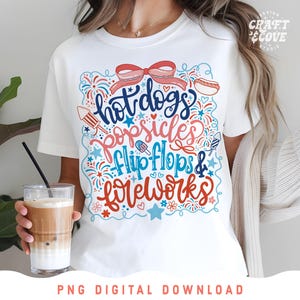 May include: White t-shirt with a colorful graphic design featuring the words "hot dogs, popsicles, flip flops & fireworks" in a playful font. The design includes illustrations of a hot dog, popsicle, and fireworks.