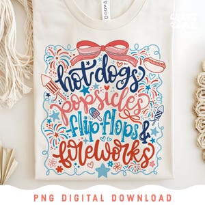 May include: Cream-colored t-shirt with a colorful graphic design. The design features the words "hot dogs, popsicles, flip flops & fireworks" in a playful font, along with illustrations of a hot dog, popsicle, fireworks, and a bow.