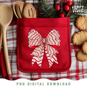May include: A red kitchen apron with a bow design, wooden spoons, and cookies. The bow is white with red stripes and green sprinkles. The apron is in a pocket shape. The background is a red and white checkered pattern.