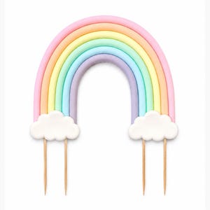 May include: A cake topper shaped like an arched rainbow with pastel bands of pink, orange, yellow, green, blue, and purple. Two white clouds are attached at the base of the rainbow, each supported by two thin, pointed wooden sticks for insertion.