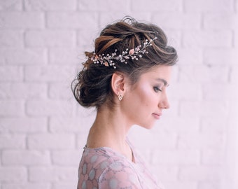 May include: A woman with a light pink and white patterned dress and a delicate floral hairpiece. She is standing in front of a white brick wall.