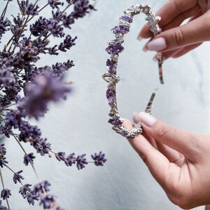 May include: A silver headband with a row of purple and clear rhinestones.