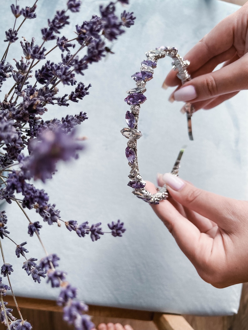 May include: A silver headband with a row of purple and clear rhinestones.
