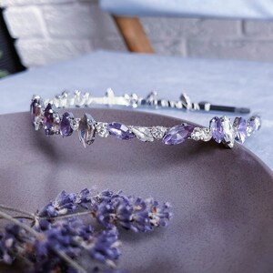 May include: A silver headband with purple and clear rhinestones in a leaf shape.